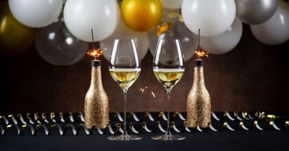 two champagne glasses with balloons in background