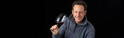 Maximilian J. Riedel holding wine glass with red wine in it