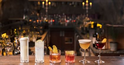 various glasses from the drink specific glassware collection, filled with different cocktails and garnish, placed on a bar