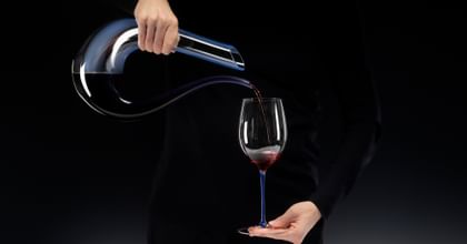 hands pouring wine from a decanter into a glass