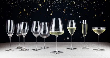 Various RIEDEL champagne glasses lined up with sparkly background
