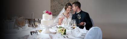 Bride and Groom sitting on a table setting with cake