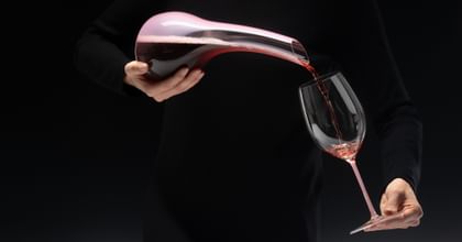 hands pouring wine from a decanter into a glass
