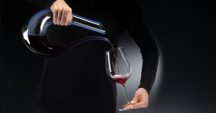 hands pouring wine from a decanter into a glass