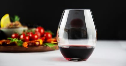 vegetable plate behind stemless red wine glass