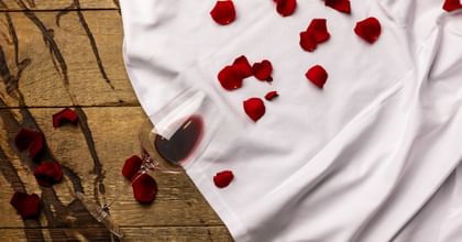 red wine glass on its side next to rose petals