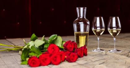 decanter and two wine glasses next to roses