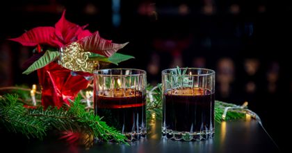 mulled wine in RIEDEL Drink Specific Double Rocks Glasses in the background is a poinsettia plant and fir branches