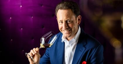 Maximilian J. Riedel holding wine glass and smiling