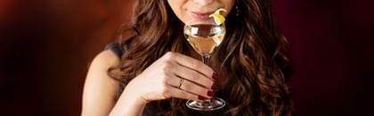 up close woman holding a cocktail in RIEDEL Drink Specific Glassware and smelling the aroma