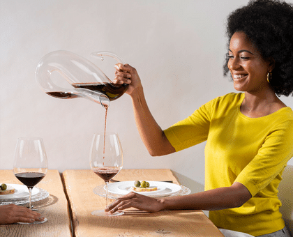 Lady pouring wine into a wine glass at table 4000x3240px