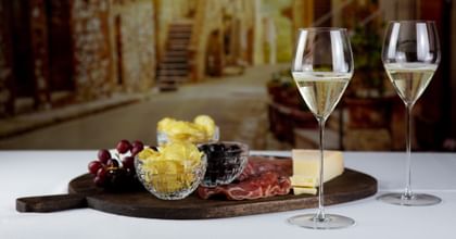 two white wine glasses in front of cheese plate