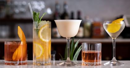 various cocktail glasses filled with different cocktails with garnish 