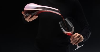 hands pouring wine from a decanter into a glass