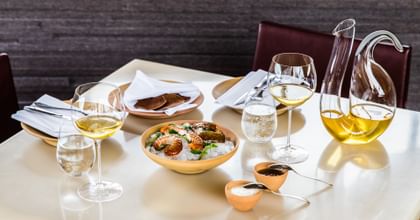 Veritas Oaked Chardonnay Glasses and a Dekanter filled with Chardonnay on a table with food