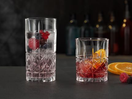 El vaso largo NACHTMANN Highland Diamond lleno de un cóctel de bayas sobre hielo junto al vaso Highland Diamond lleno de un Negroni.<br/>