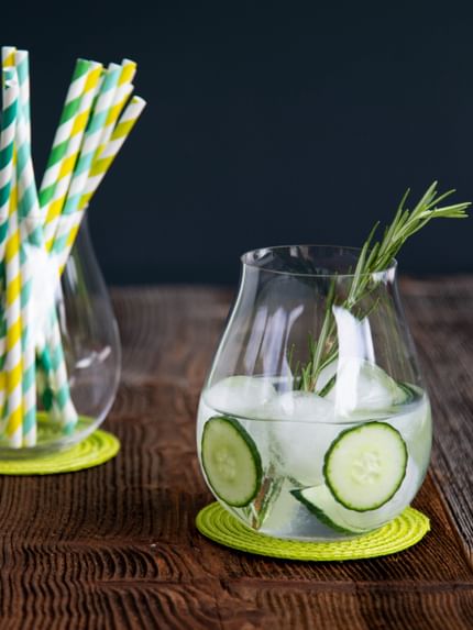 gin and tonic in glass next to straws