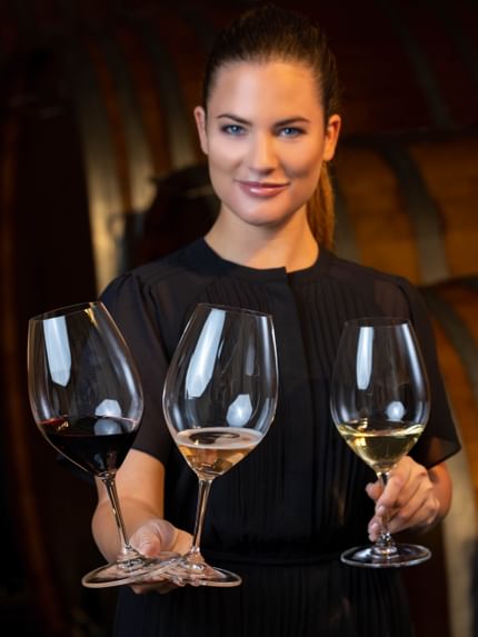 woman holding 3 wine glasses