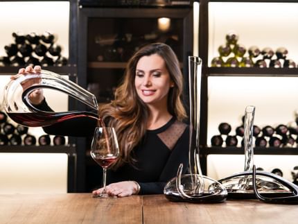 Lady pouring red wine out of the RIEDEL Amadeo into a wine glass.