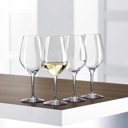 Vier kleine SPIEGELAU Authentis Weißweingläser auf einem Tisch, eines davon ist mit Weißwein gefüllt.<br/>