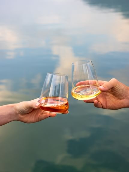 holding white wine glasses near lake