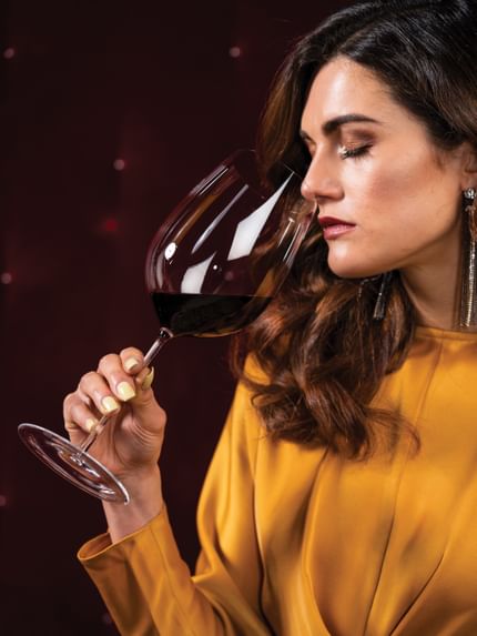 Lady sniffing red wine out of a Sommeliers Bordeaux Grand Cru glass.