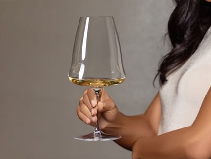 Lady holding RIEDEL Winewings glass filled with white wine.