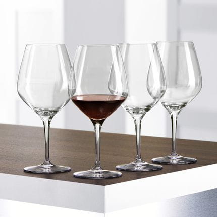Four SPIEGELAU Authentis Burgundy glasses on a table, one of them is filled with Burgundy wine.<br/>