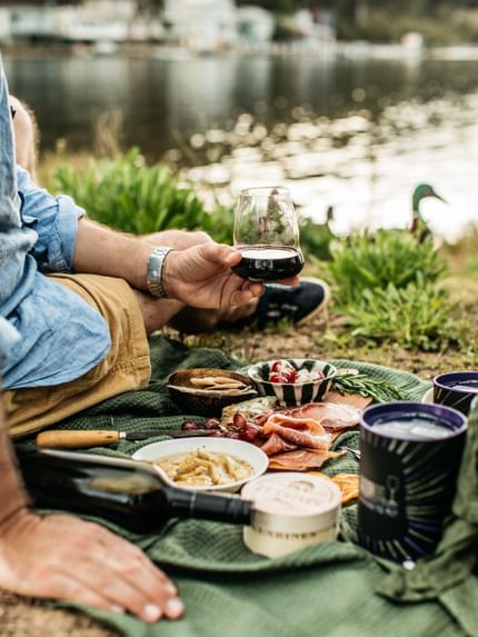 a man holding a Riedel stemless Winewings glass infront of a lake