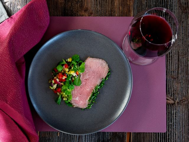 steak on a plate next to red wine glass shot from above