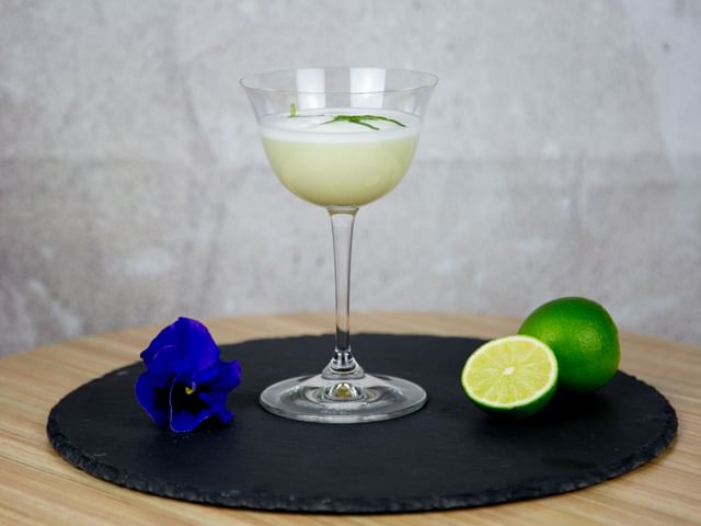 lime cocktail on table next to limes