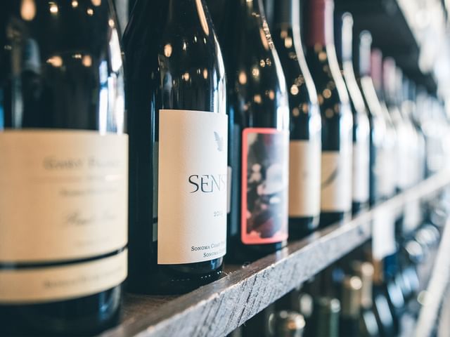 A line of wine bottles on a wooden shelf.
