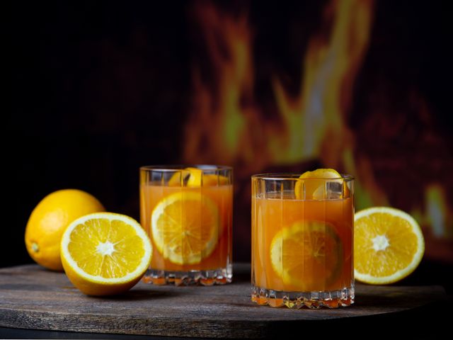 Hot Aperol in 6417/07 RIEDEL Drink Specific Glassware Double Rocks Glas in the background is a fireplace and oranges