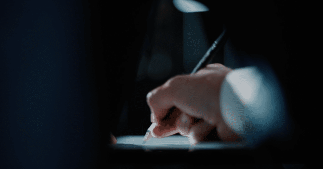 Close-up of a designer’s hand sketching with a pencil under soft lighting, symbolizing the artistry and meticulous design process behind RIEDEL glassware.