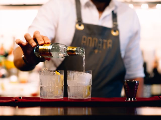 Two RIEDEL Shadows Whisky Tumblers filled with G&T with Tonic being poured into them by man.