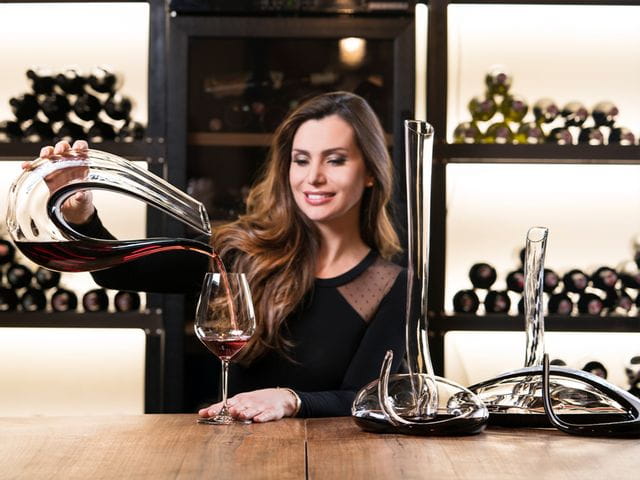 Lady pouring red wine out of the RIEDEL Amadeo into a wine glass.