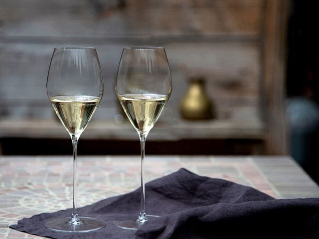 Two RIEDEL Performance Sauvignon Blanc glasses filled with white wine.