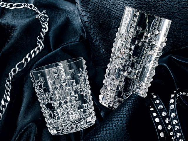 The NACHTMANN Punk whisky tumbler and the longdrink glass lying on a leather jacket with rivets and a chain.<br/>