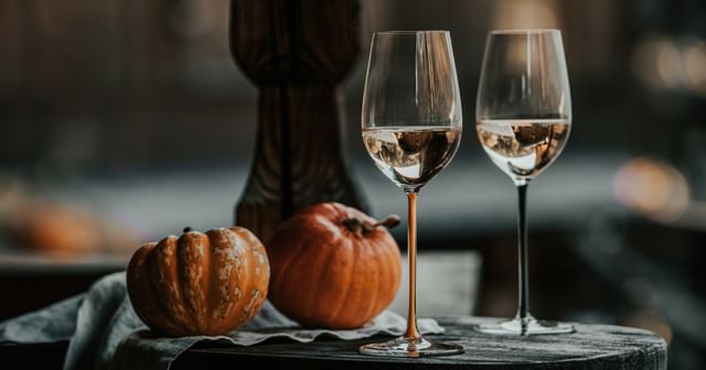two RIEDEL Fatto a Mano glasses next to pumpkins