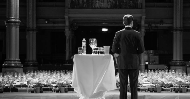 MJR photographed from behind during a tasting on stage, black and white