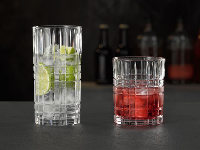 Il bicchiere longdrink NACHTMANN Highland Square riempito con una bevanda chiara con lime e cubetti di ghiaccio e il tumbler riempito con una bevanda Campari con ghiaccio.<br/>