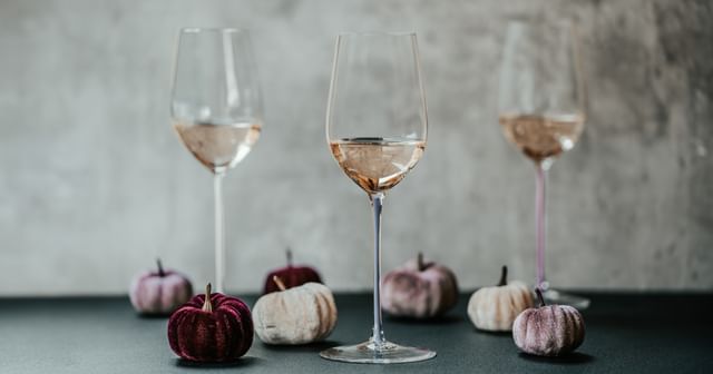 three RIEDEL wine glasses surrounded by white pumpkins