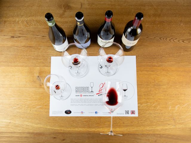 Tasting mat with 2 different white wine glasses and two different red wine glasses of the RIEDEL Veloce series all empty, two different white wine bottles and two different red wine bottles from above (bird's eye view)