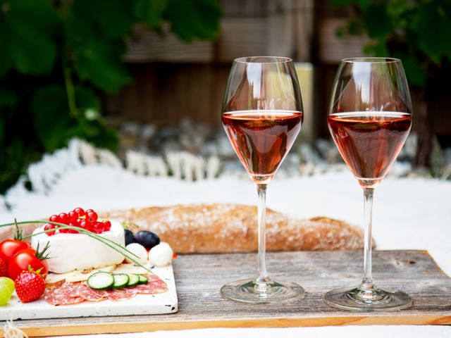 two wine glasses next to bread and cheese plate