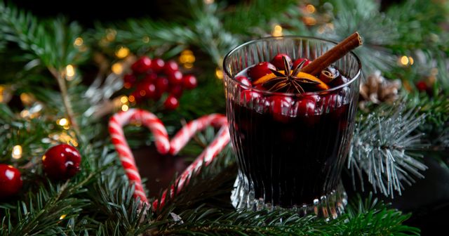 mulled wine in a RIEDEL Fire Glass in the background are two candy canes and fir branches