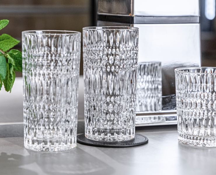 Two empty NACHTMANN Ethno longdrink glasses on a sideboard, left of them an Ethno tumbler with mint sprigs.<br/>